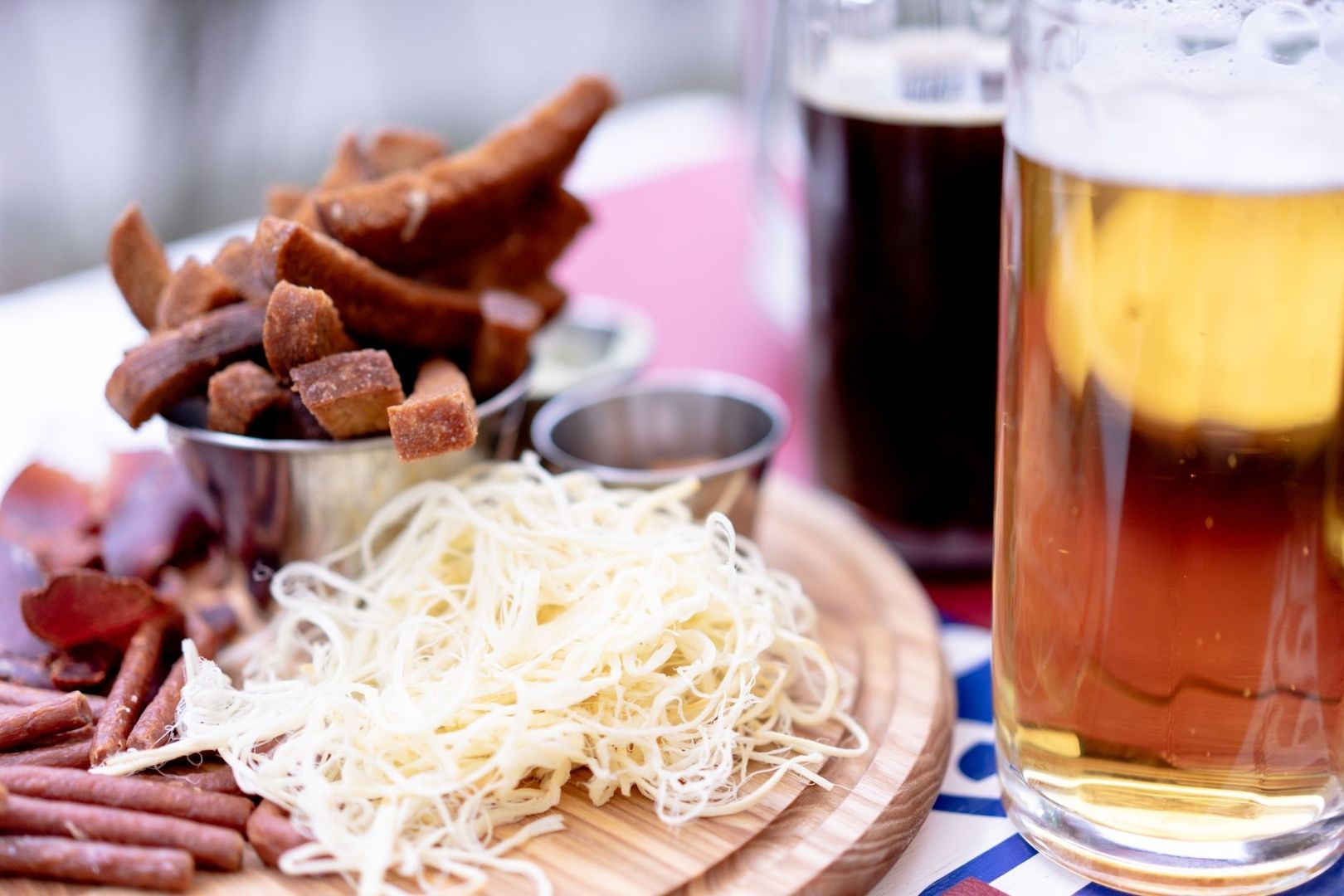 Rustic wooden platter with sliced meats, grated cheese, and beer