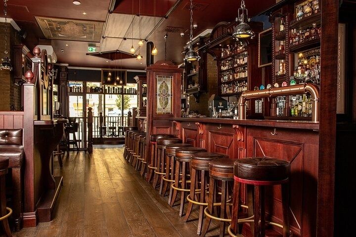 Traditional wood-paneled tavern interior with a long bar and stools